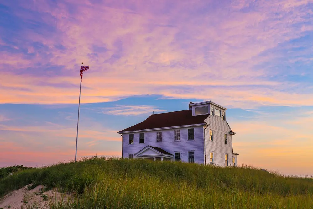A bright pink, purple, and blue sky during sunset at a peak in Cape Cod