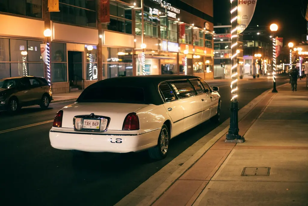 Chauffeured limo parked outside a city building at night, representing private car service for Boston World Cup transport