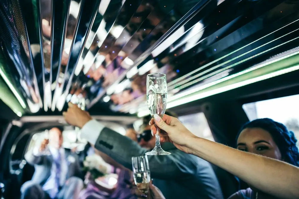 Guests raising champagne glasses inside a party executive limousine in Boston