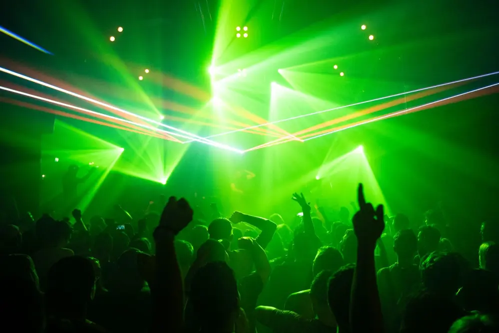 Crowd dancing under green laser lights at a Boston nightclub event